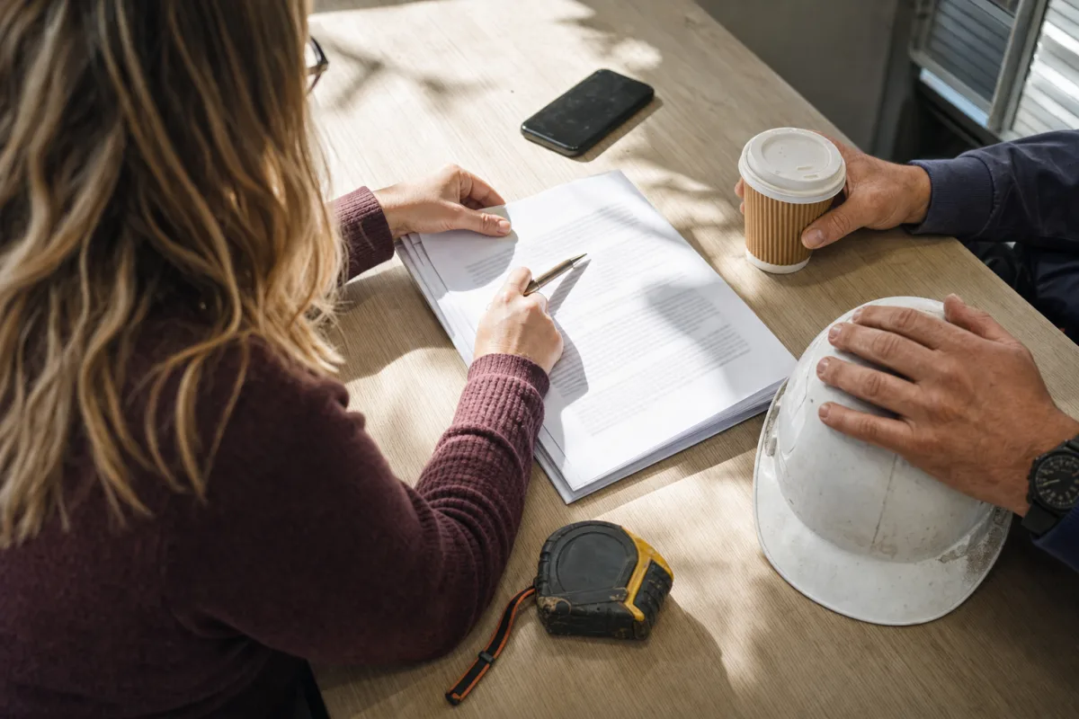 Ashleigh and a site manager going through a written proposal on a site office table